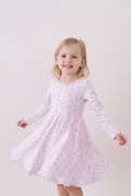 Young girl wearing a pink dress with a subtle pattern on a white background